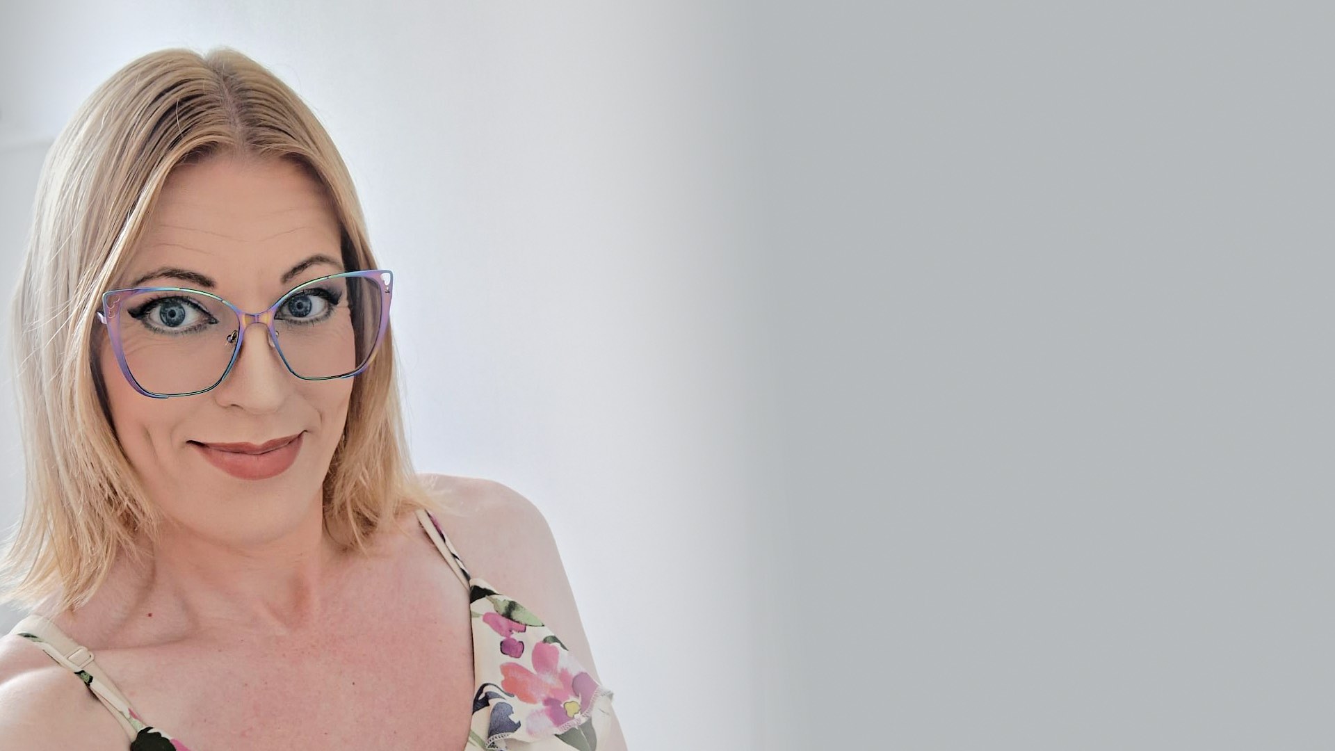 A photo of Ami Foxx wearing a pair of colourful framed glasses, smiling at the camera.