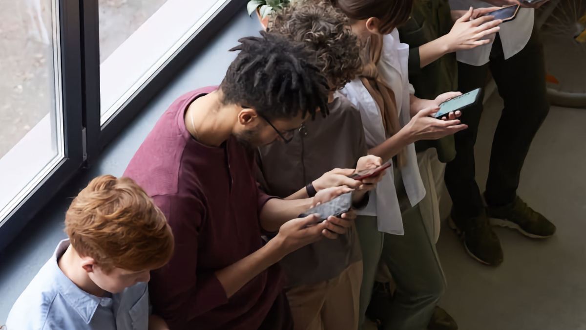 A group of people lined up all fixed to the screens on their phone